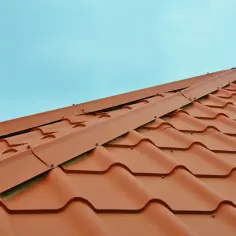 Nowe, brązowe dachówki tworzą łagodną pochyłość. Zastanawiasz się, jak obliczyć kąt dachu?
