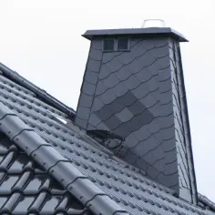 Nowy komin z obróbką struktonitem, pokryty ciemną dachówką, prezentuje się solidnie.