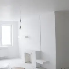 Nowe, ciekawe zabudowy z płyt gipsowych tworzą nowoczesny kominek i półki. Pokój w trakcie remontu.