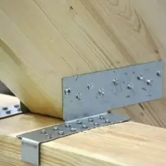 Solidne łączenie desek na zakładkę za pomocą metalowych kątowników i wkrętów. Konstrukcja drewniana zyskuje stabilność.