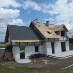 Budowa domu w toku. Na jednej połaci dachu położono papę, druga czeka na deskowanie dachu czy warto.