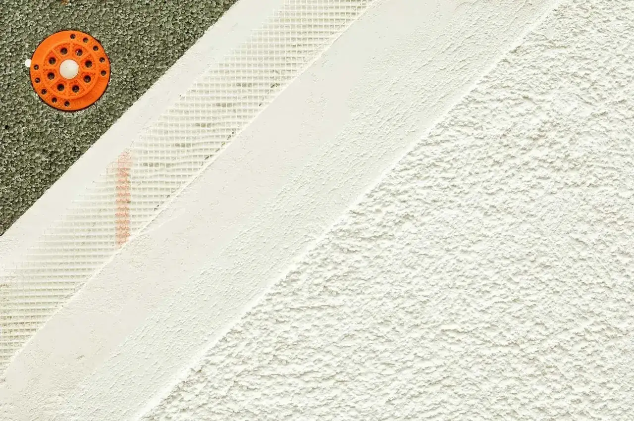 Warstwowa struktura elewacji: styropian z kołkiem, siatka zbrojąca i biały puc na elewację tworzą nowoczesny design.