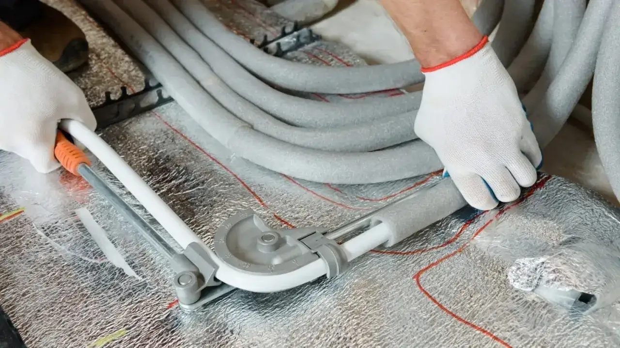 Instalator zgina rury PEX do centralnego ogrzewania za pomocą giętarki.