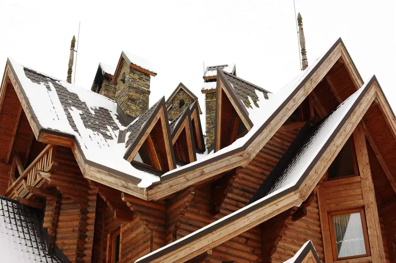 Drewniana nadbudówka z oknem w dachu, pokrytym śniegiem.