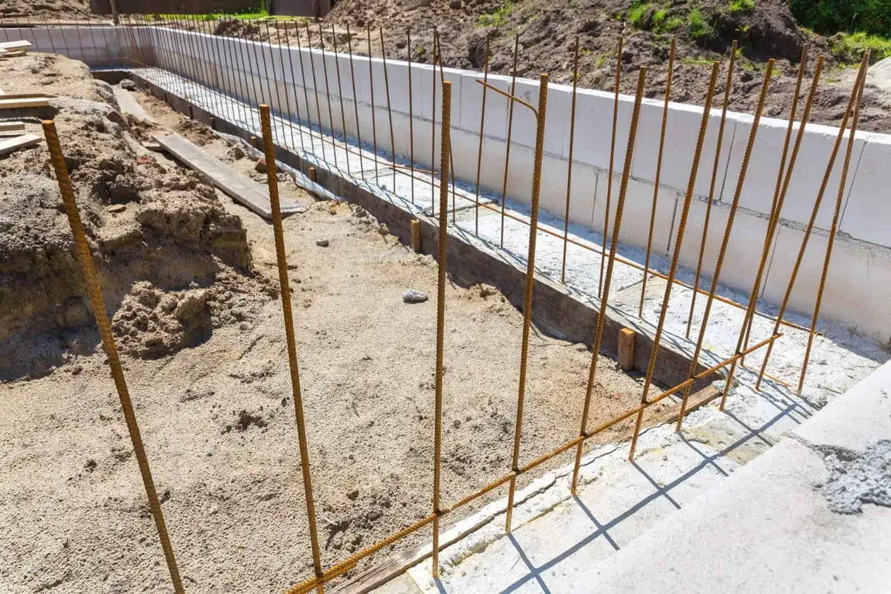 Zbrojenie fundamentów gotowe do zalania betonem. Widać pionowe i poziome pręty, które wzmocnią konstrukcję. To kluczowy etap, jak krecic zbrojenie.