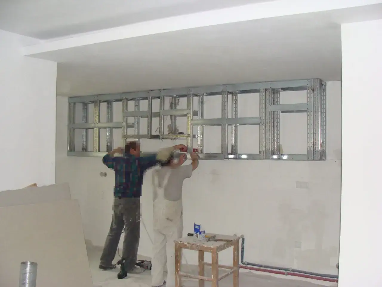 Dwóch mężczyzn montuje stelaż pod szafę z karton gipsu.