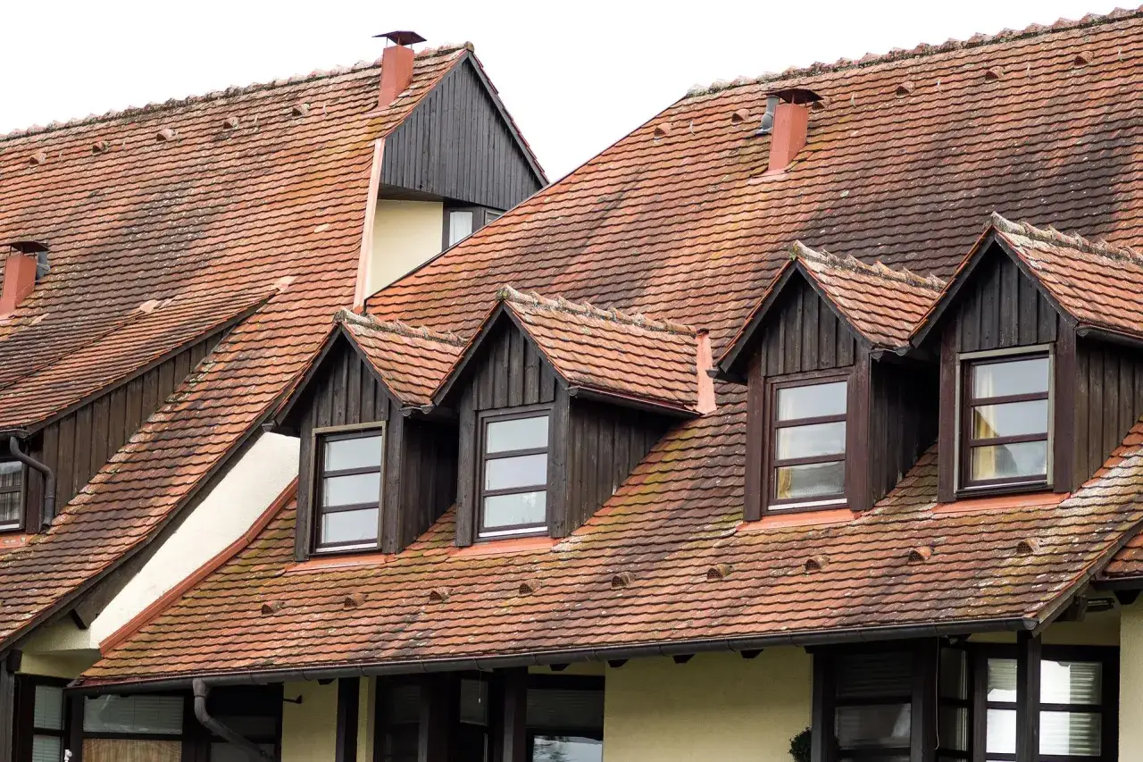 Dachówki dachowe z kilkoma lukarnami w dachu, każda z drewnianą obudową i oknem.